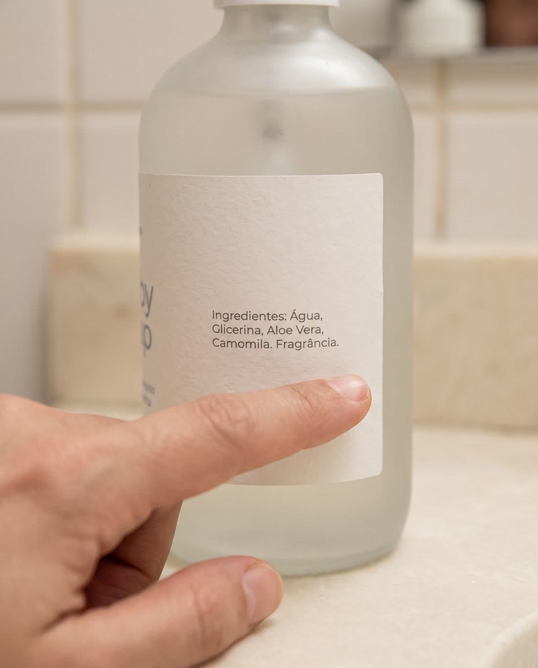 Dedo apontando para a palavra Fragrância no rótulo de um frasco de sabonete infantil.