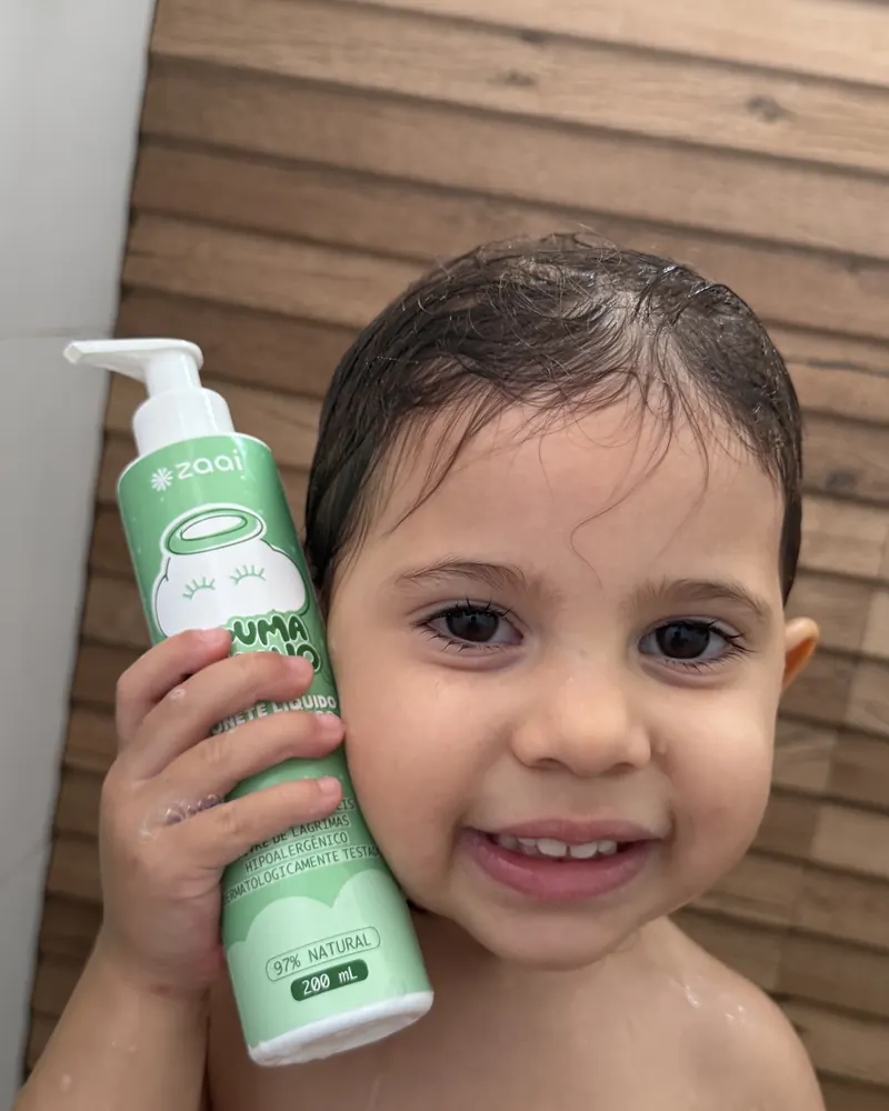 Crian&ccedil;a sorrindo com o frasco encostado no rosto
