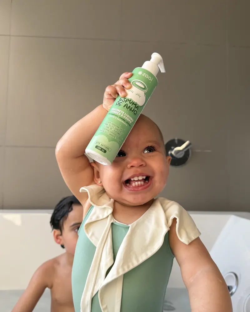 Beb&ecirc; rindo com o frasco da Espuma de Anjo na cabe&ccedil;a
